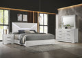 Modern bedroom with white furniture set including bed, nightstands, and dresser.