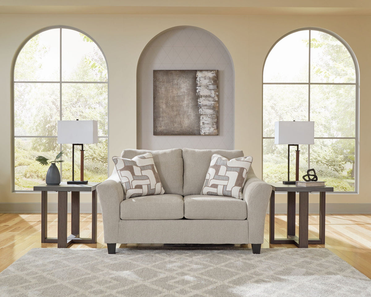 Gray sofa with patterned cushions in a living room setting with arched windows and lamps.