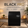 Black Pro portable far infrared sauna for home wellness and professional use. Black portable far-infrared sauna machine with quilted diamond pattern and Relax branding, shown in a styled home interior with warm lighting and informational text above.