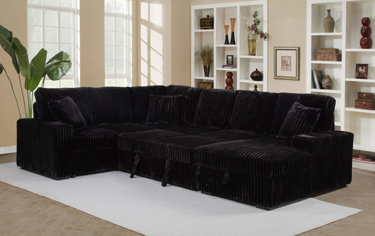 Black sectional sofa in a living room with bookshelves and decor.