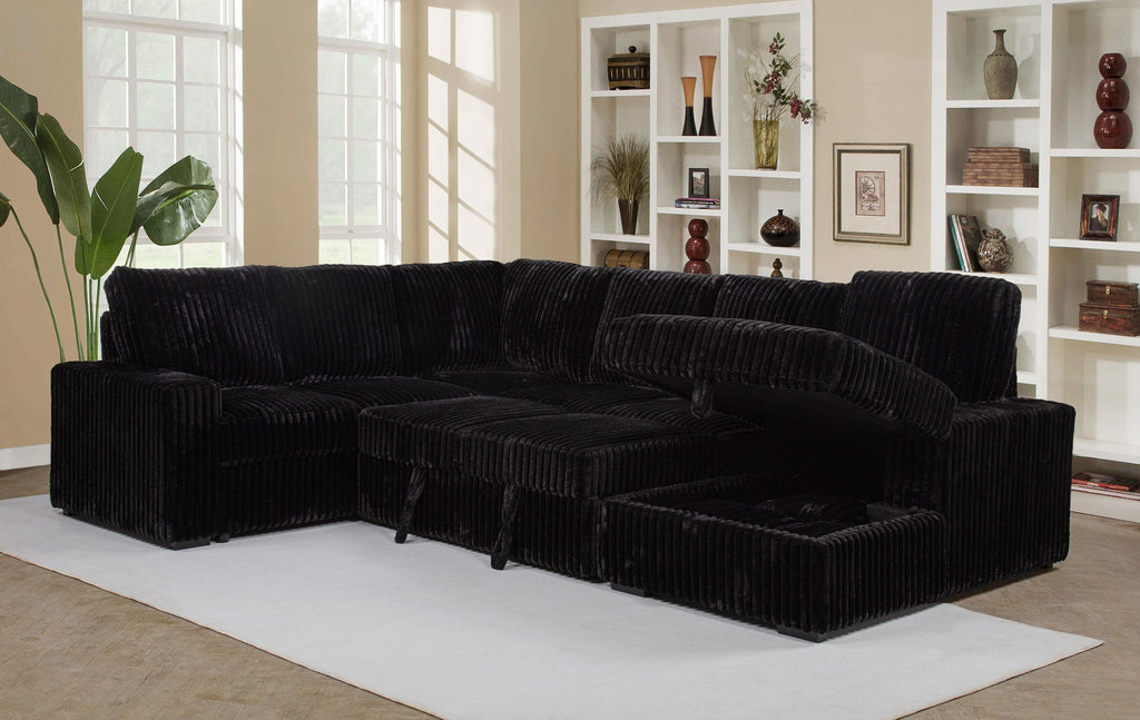 Black sectional sofa in a living room with bookshelves and decor.
