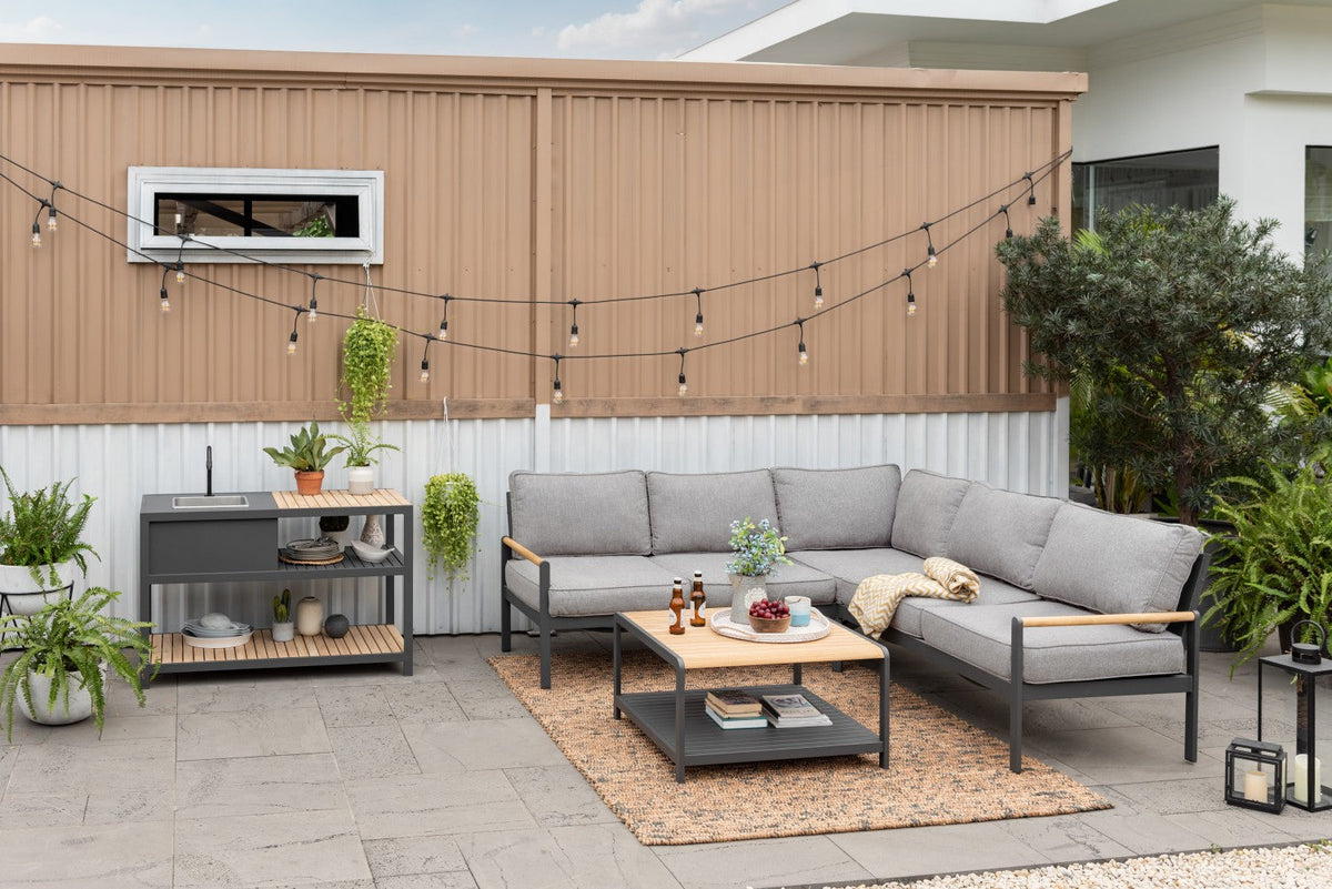 Outdoor patio with gray sectional sofa, coffee table, and decorative elements on a patio.